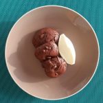 Dark chocolate brookies, on a beige plate, served with quenelle of cream green background